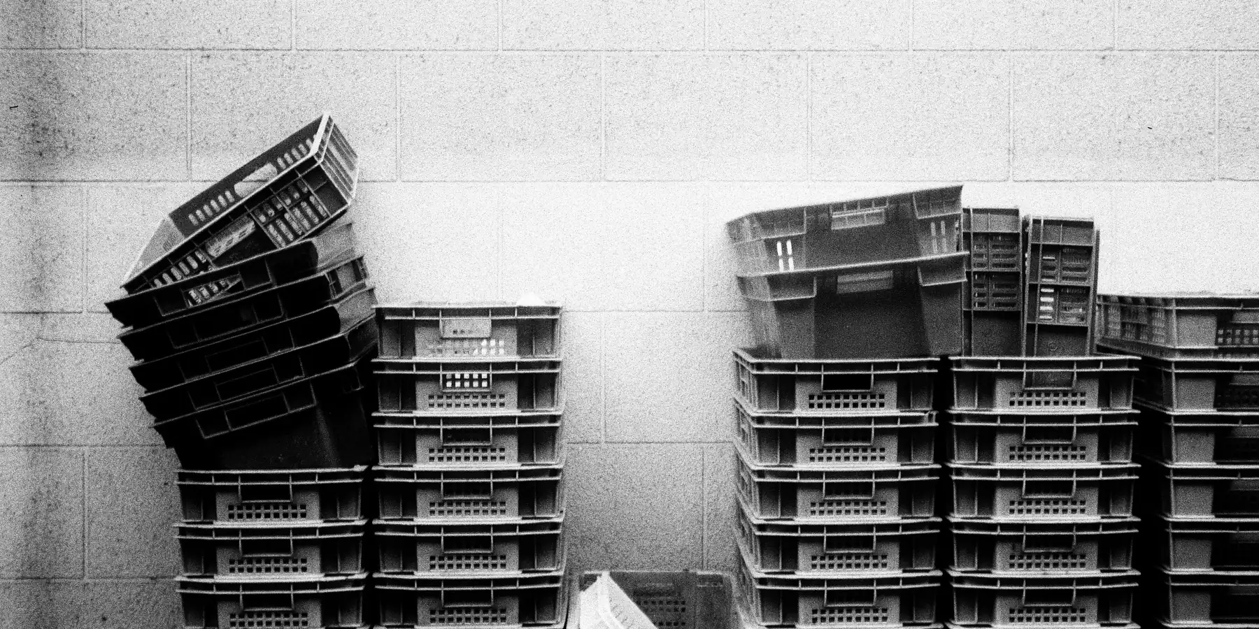 Stacks of plastic crates piled against a pale wall