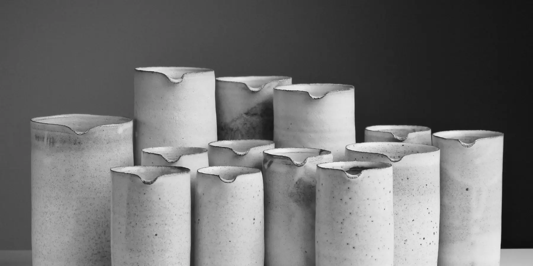 Cluster of white speckled ceramic pitchers against a dark grey backdrop