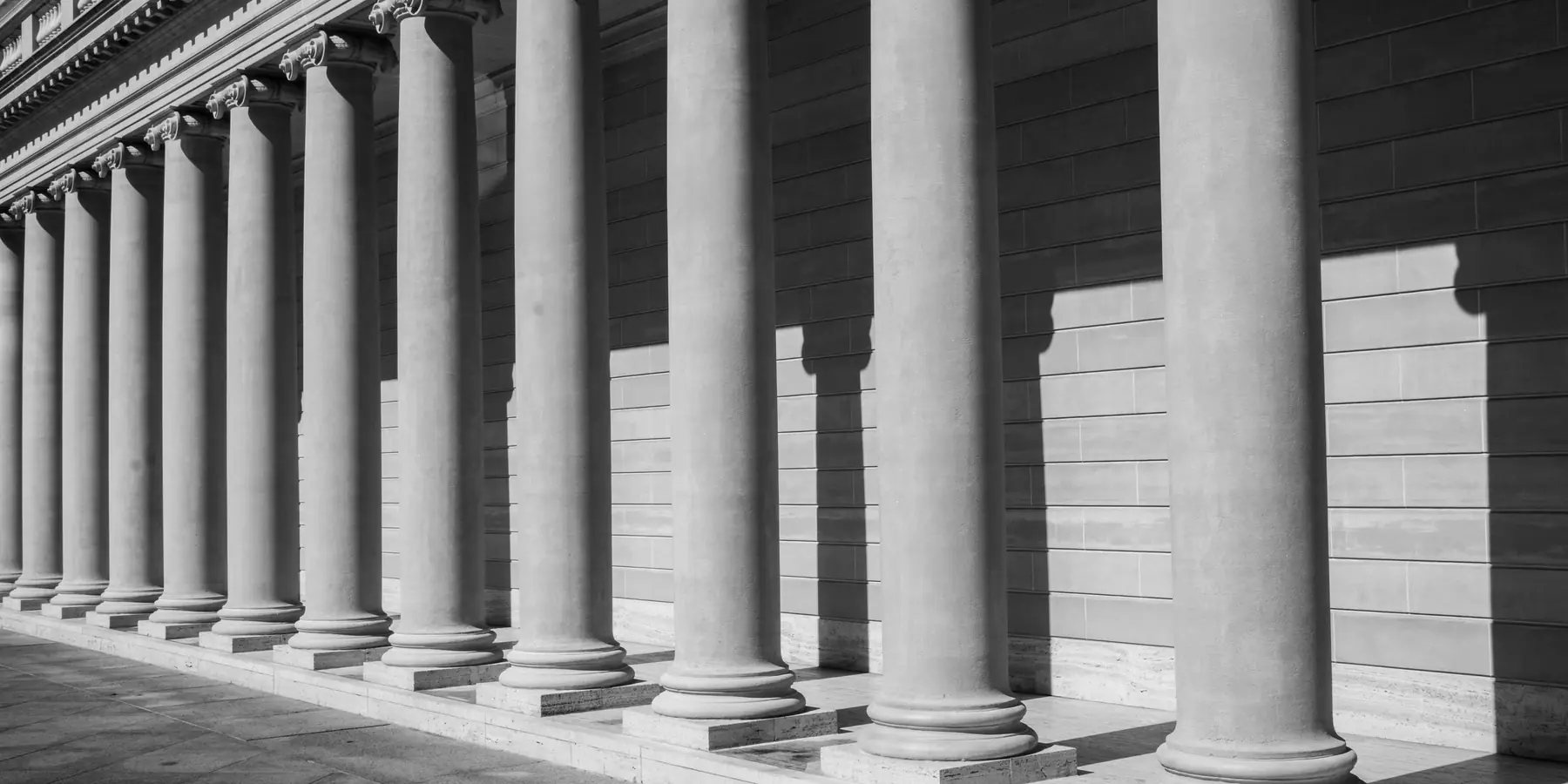 Row of stone columns casting long shadows along a colonnade