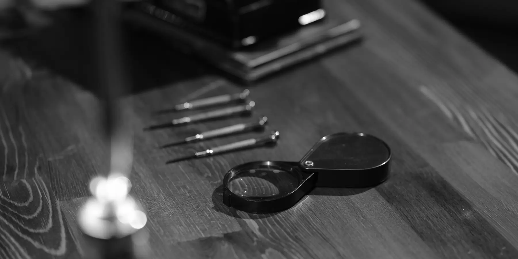 Folding jeweller's loupe and small screwdrivers lying on a dark wooden workbench