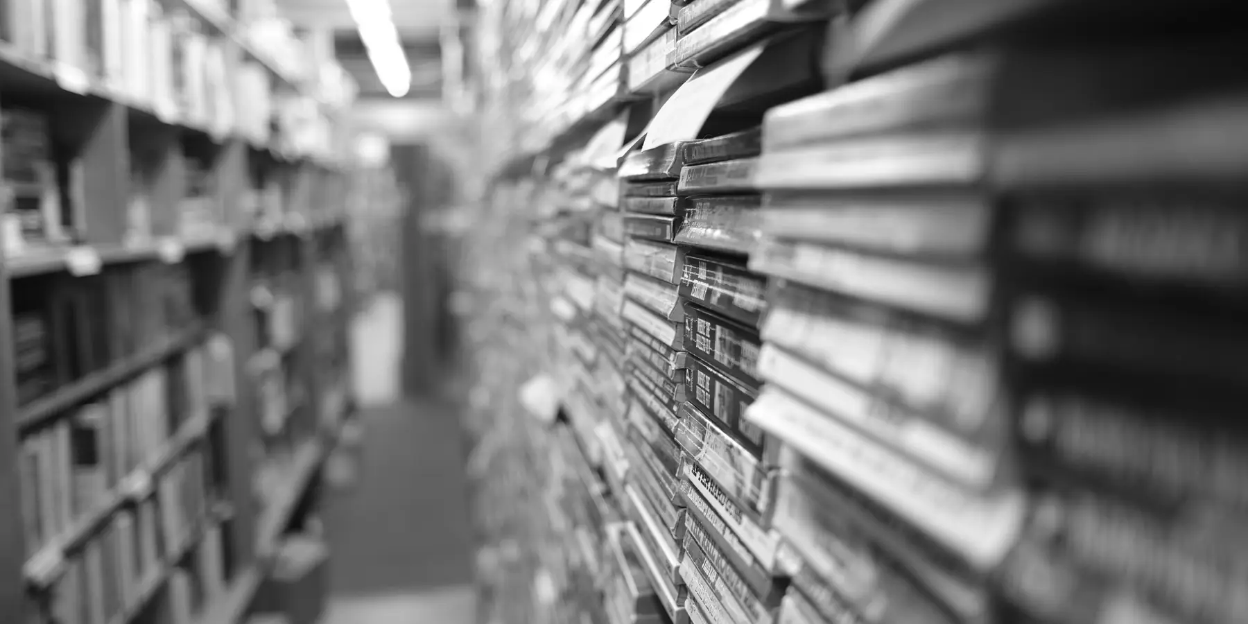 Narrow library aisle between tall shelves of books, softly out of focus