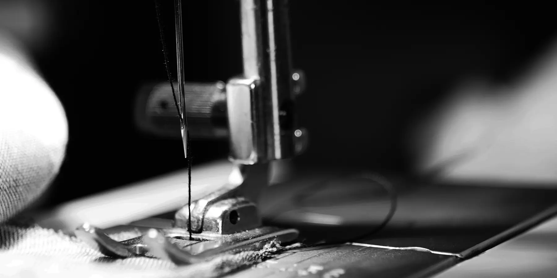 Close-up of a sewing machine needle and presser foot over fabric