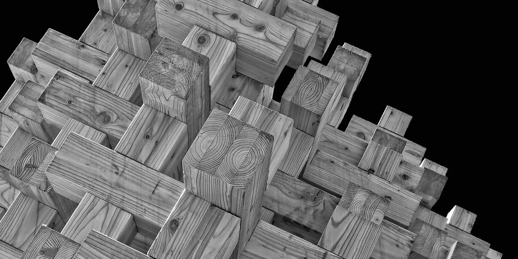 Interlocking rough timber beams stacked in layers against a black background