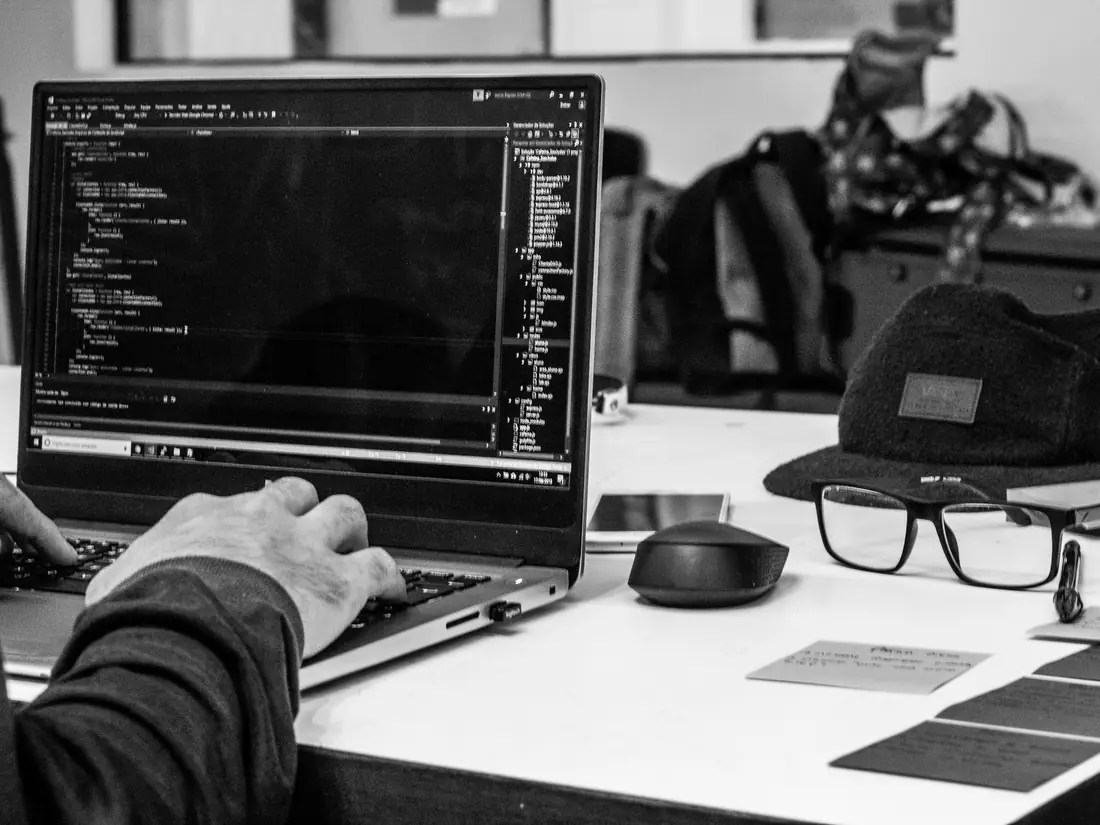 Hands on a laptop keyboard showing code, in black and white