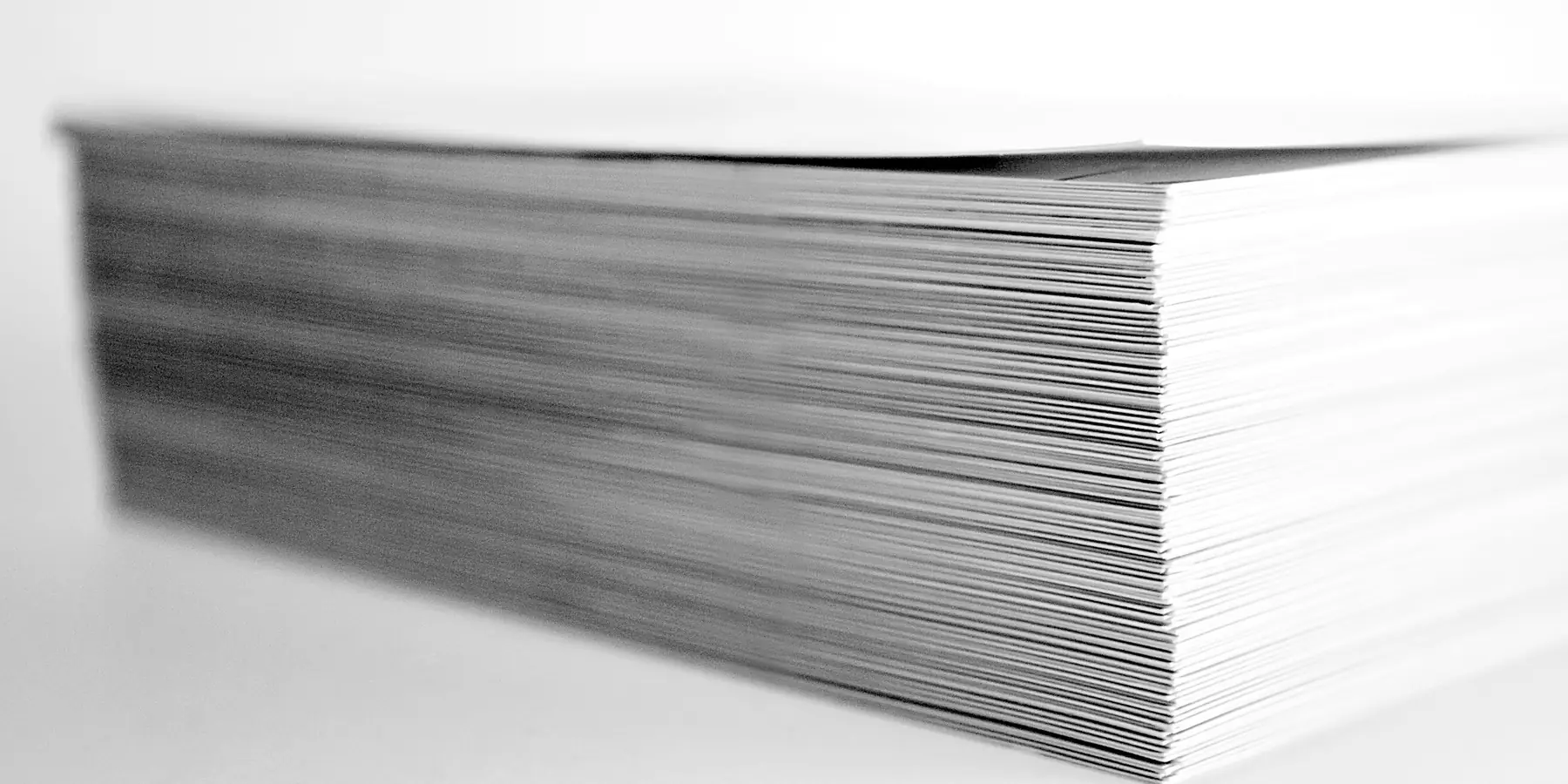 Edge of a thick stack of white paper sheets on a pale surface
